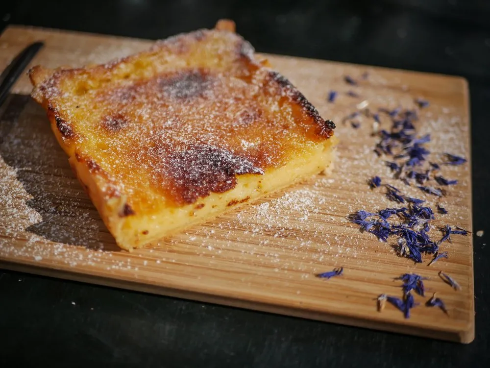 Dessert maison caramélisé saupoudré de sucre, parsemé de pétales de bleuet